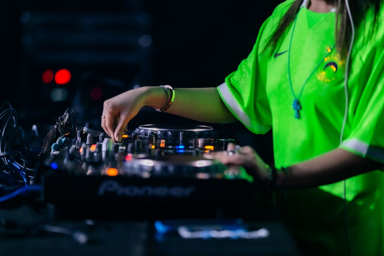 Close-up of DJ mixing electronic music at a nightclub with vibrant lighting.