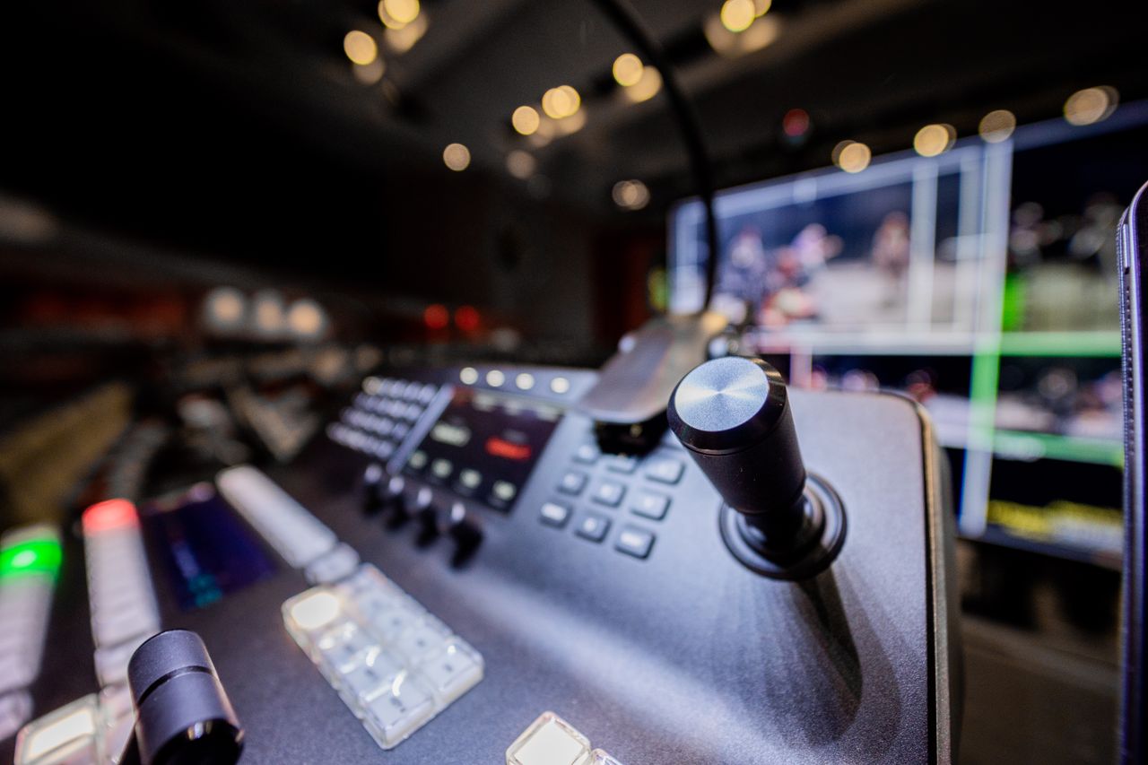 Home Closeup of modern professional audio console controller with buttons placed near screen in studio with lights